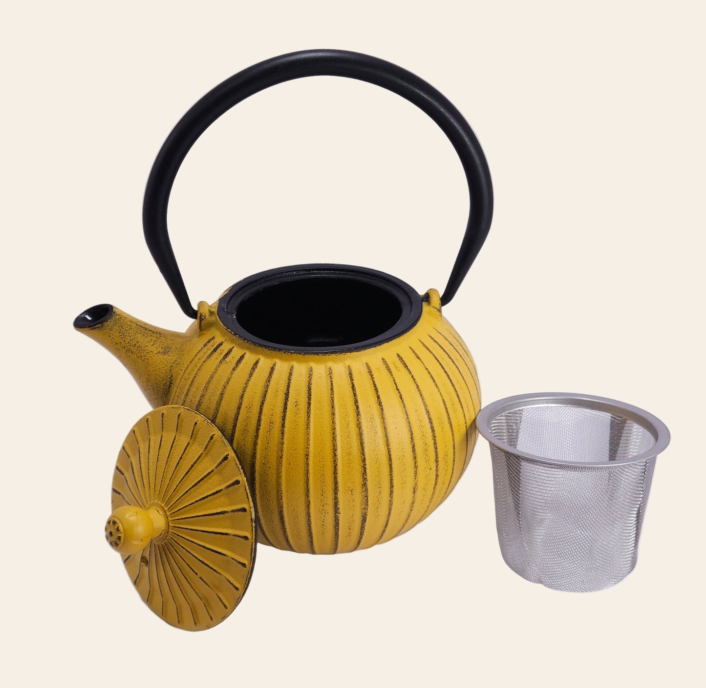 Théière en fonte jaune 800 ml, anse relevée, détail visible du filtre en acier inoxydable