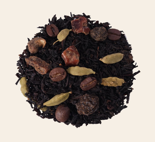 Mélange de thé noir en vrac avec capsules de cardamome entière, morceaux de dattes, raisins secs et grains de café torréfiés.